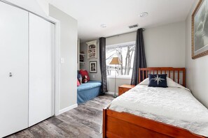 Une chambre à coucher avec un lit en bois, une table de chevet, un bureau, une chaise et une armoire.