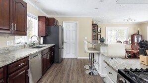 A modern kitchen with dark wooden cabinets, a stainless steel refrigerator, a marble countertop, and a gas stove. - Silver Lake Waterfront Home, Traverse City, MI (Traverse City)