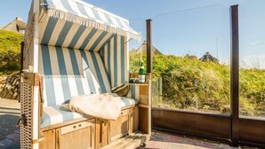Una cama con dosel a rayas, junto a un aparador de madera y una mesita, con vistas a un paisaje pintoresco.