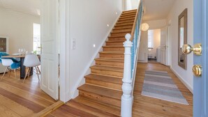 Un escalier avec des marches en bois et des balustrades blanches, menant à un deuxième étage.