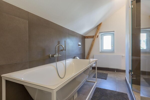 A modern bathroom with a large bathtub, a shower, and a glass-enclosed shower area.