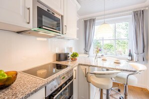 A modern kitchen with a built-in oven, a microwave, and a large window with curtains.