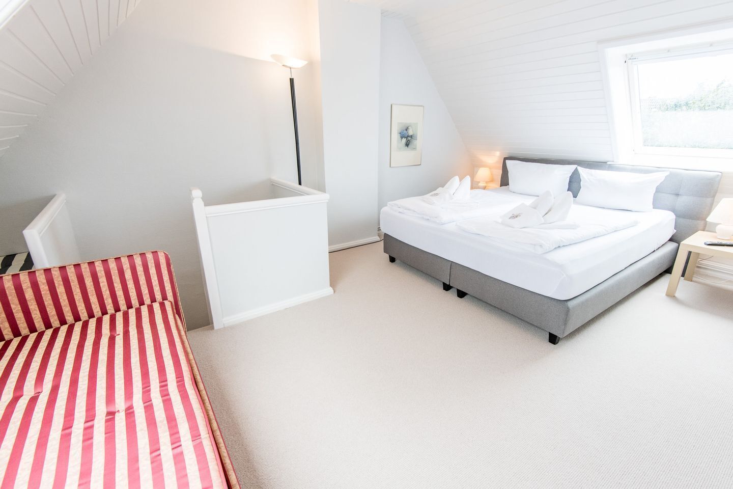 A bedroom with a bed, bedside table, lamp, and a window.