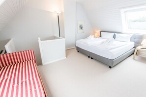 A bedroom with a bed, bedside table, lamp, and a window. - Ostertresker 54, an island oasis (Sylt-Ost)