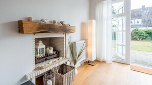 Ein gemütliches Zimmer mit Kamin, großem Fenster und Blick ins Freie.