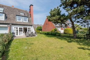 A residential property with a well-maintained lawn, a patio with outdoor furniture, and a brick chimney.