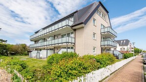 A multi-story residential building with balconies, a brick facade, and a garden area. - House Doktor-Ross-Straße 25, Whg. 19 Wunderkammer (Sylt)