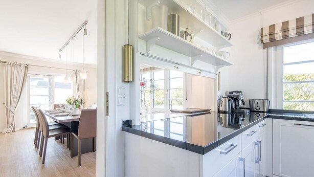 A modern kitchen with white cabinetry, a black countertop, and stainless steel appliances. - Country house Tinnumburg, Germany (Sylt-Ost)