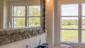 A bathroom with a large window offering a view of a grassy field and trees. - Country house Tinnumburg, Germany (Sylt-Ost)