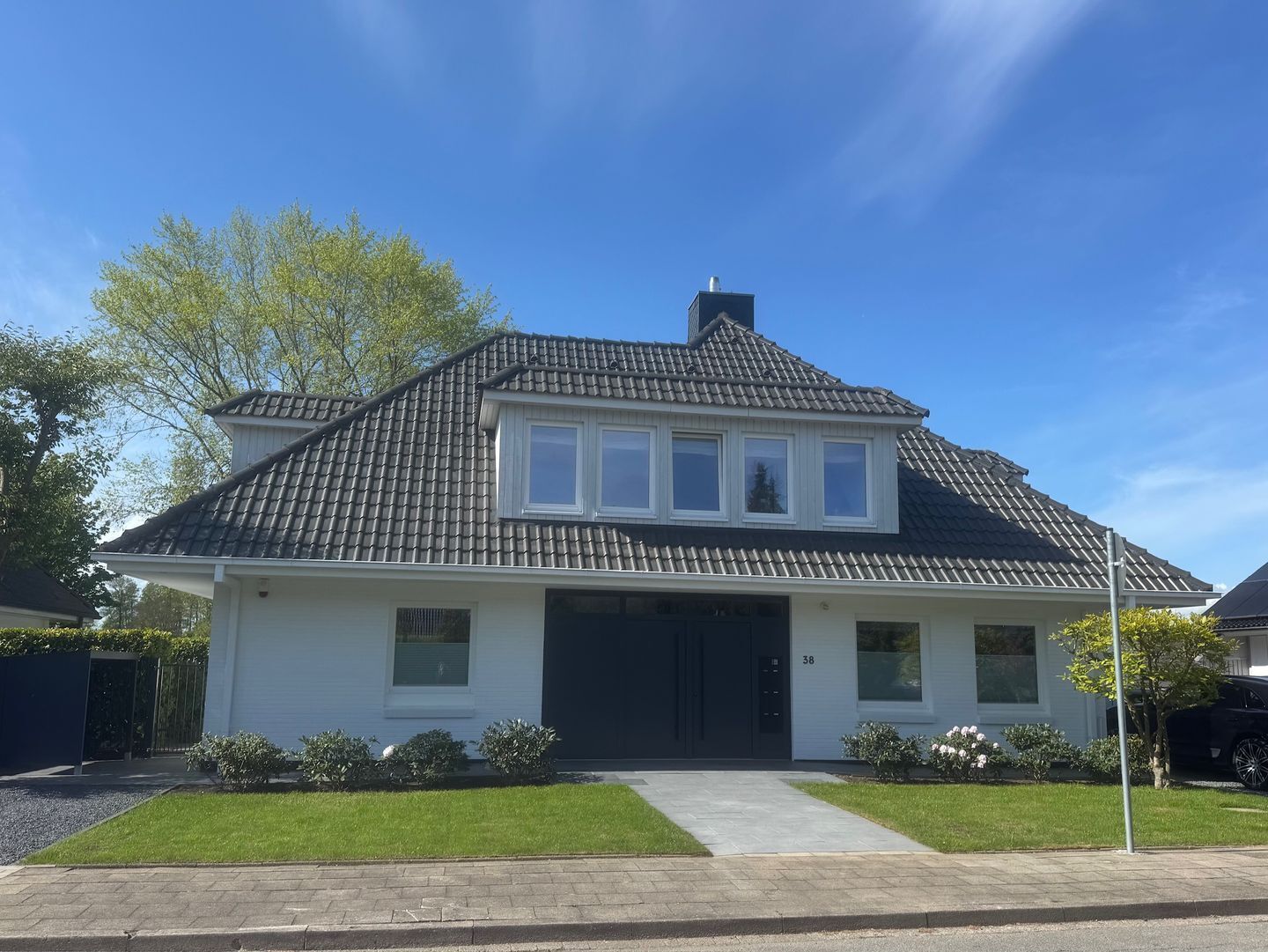 Ein zweistöckiges Haus mit dunklem Dach, weißem Außenbereich und einer Garage.