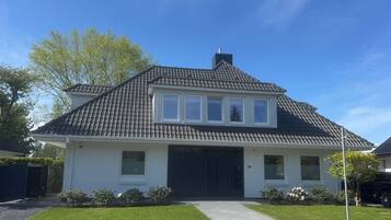 Ein zweistöckiges Haus mit dunklem Dach, weißem Außenbereich und einer Garage.
