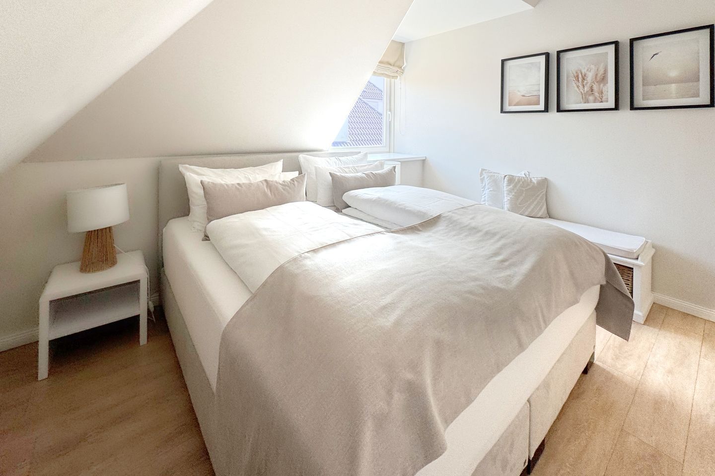 A bedroom with a large bed, a bedside table with a lamp, and a window with a view.