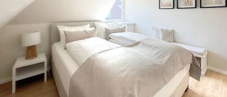 A bedroom with a large bed, a bedside table with a lamp, and a window with a view.