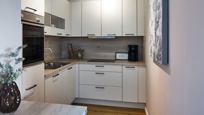 A compact kitchen with white cabinets, a built-in oven, a coffee maker, and a small sink. - Experience relaxation at TECHTs Apartmenthaus StrandPerle on Timmendorfer Strand (Timmendorfer Strand)