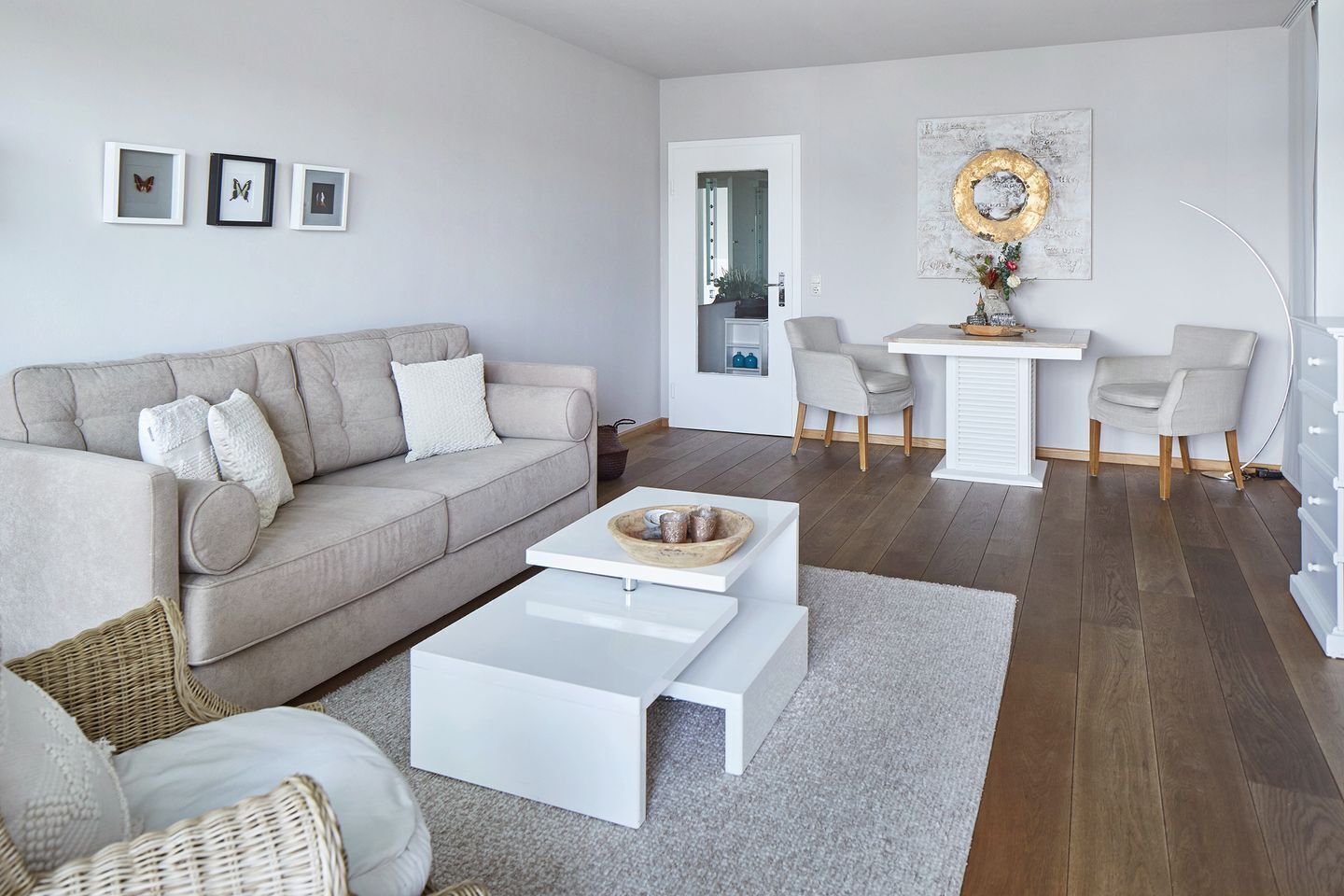 Una sala moderna con sofá, mesa de centro, sillas y una zona de comedor con mesa y sillas.