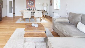 Ein modernes Wohnzimmer mit einem Holztisch, einem grauen Sofa und einem Essbereich mit Tisch und Stühlen.