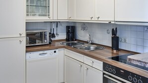 A modern kitchen with white cabinetry, a Bosch dishwasher, a Bosch coffee maker, a Bosch toaster, and a stainless steel sink. - Welcome to TECHTS - TECHTs Apartmenthaus (Timmendorfer Strand)
