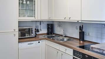 Eine moderne Küche mit weißen Schränken, einem Geschirrspüler von Bosch, einer Kaffeemaschine von Bosch, einem Toaster von Bosch und einer Spüle aus Edelstahl.