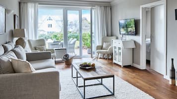 Ein modernes Wohnzimmer mit einer Sofagarnitur, einem Couchtisch und einem Fernseher.