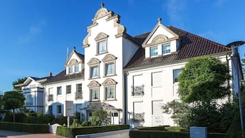 Ein großes, weißes, mehrgeschossiges Gebäude mit einer symmetrischen Fassade, einem zentralen Turm und einem roten Ziegeldach.
