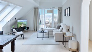 Ein modernes Wohnzimmer mit Fernseher, Sofa, Couchtisch und Essbereich.