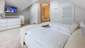A bedroom with a large bed, a TV on the wall, a desk, and a chair. - "Meerzeit" maisonette apartment - stylish living at Timmendorfer Platz - TECHTs (Timmendorfer Strand)