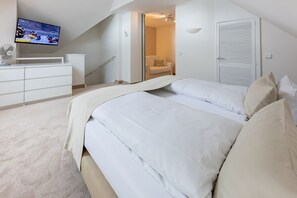 A bedroom with a large bed, a TV on the wall, a desk, and a chair. - "Meerzeit" maisonette apartment - stylish living at Timmendorfer Platz - TECHTs (Timmendorfer Strand)