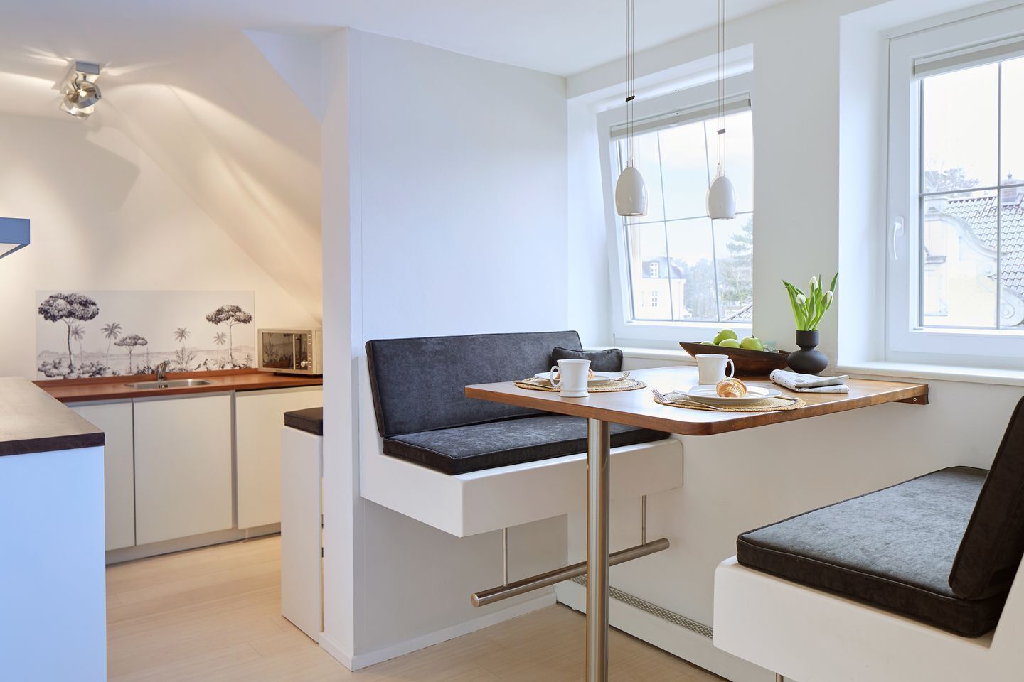 Een moderne keuken met een ingebouwde bank en een eethoek, een magnetron en een raam met uitzicht.