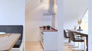 A modern kitchen with white cabinets, a wooden countertop, and a built-in stove.