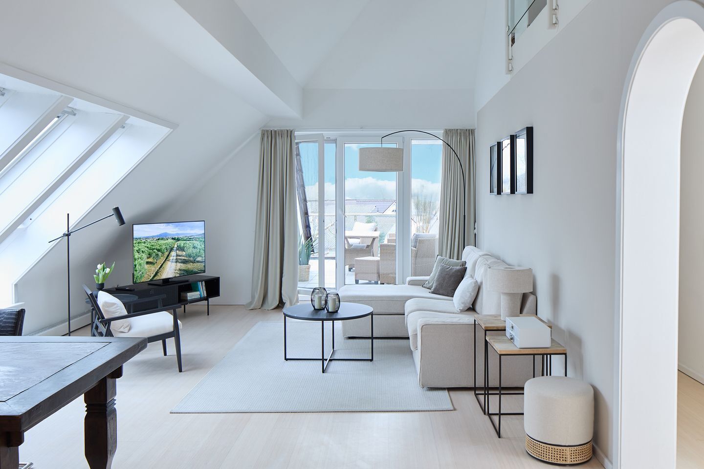 A modern living room with a TV, sofa, coffee table, and a dining area.