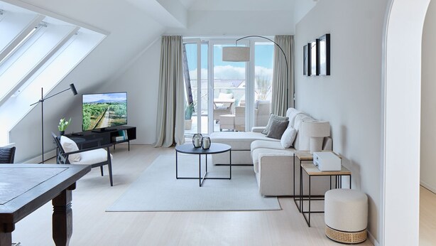 A modern living room with a TV, sofa, coffee table, and a dining area.