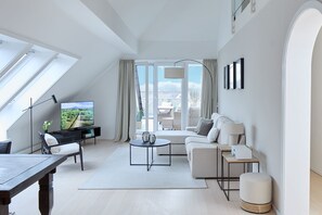 A modern living room with a TV, sofa, coffee table, and a dining area.