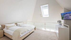 Ein Schlafzimmer mit Bett, Fernseher, Schreibtisch und Balkon.