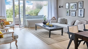 A spacious living room with a large sliding glass door leading to a balcony, a sofa set, a coffee table, and a dining area. - Apartment "Seestern" - Stylish retreat with terrace and beautiful view (Timmendorfer Strand)