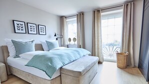 A modern bedroom with a large bed, bedside tables, and a view of the outdoors. - Apartment "Seestern" - Stylish retreat with terrace and beautiful view (Timmendorfer Strand)