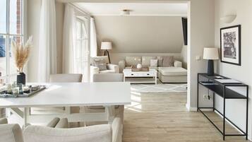 Un salon moderne comprenant un coin repas, un ensemble de canapés, une table basse et une table d’appoint avec une lampe.