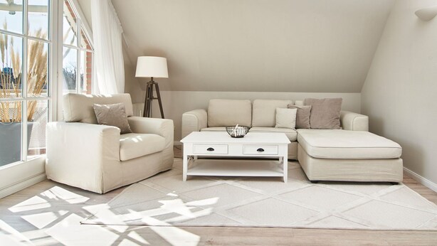 Ein modernes Wohnzimmer mit einer Sofagarnitur, einem Couchtisch und einer Lampe.