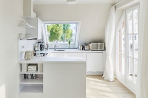 Una cocina moderna con un ventanal grande, armarios blancos y microondas integrado.