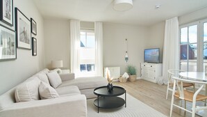 A modern living room with a sofa, coffee table, TV, and dining area.