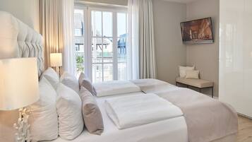 A hotel room with a bed, a nightstand, a lamp, a window with curtains, and a painting on the wall.