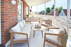 Un balcon aménagé avec un canapé, des chaises et une table, donnant sur un quartier résidentiel.