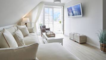 A modern living room with a sofa, a coffee table, a chair, a TV, and a window with a view.