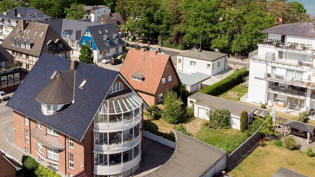 A residential area with a mix of modern and traditional houses, a curved building with balconies, and a view of the sea. - Welcome to TECHTS - TECHTs Strandhaus (Timmendorfer Strand)