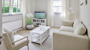 A modern living room with a sofa, armchair, coffee table, and a television on a white cabinet. - Welcome to TECHTS - TECHTs Strandhaus (Timmendorfer Strand)