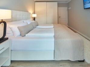 Une chambre d’hôtel bien aménagée, avec un grand lit, une table de chevet avec une lampe, une armoire et un téléviseur fixé au mur.