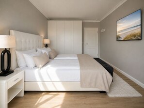 A bedroom with a bed, bedside tables, a nightstand, a wardrobe, and a painting on the wall.
