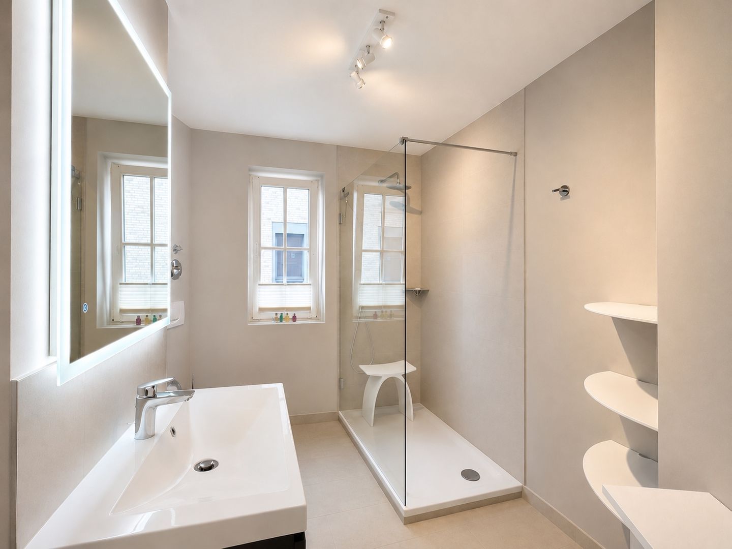 A modern bathroom with a large sink, a glass shower enclosure, and a white pedestal sink.