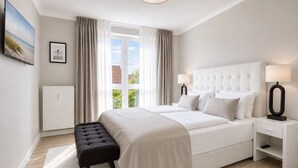 A modern bedroom with a large bed, bedside lamps, a bench, and a view of the outdoors. - A Love for the Coast – The Baltic Sea Up Close - TECHT's Beach House (Timmendorfer Strand)