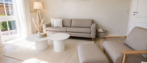A living room with a sofa, two side chairs, a coffee table, a lamp, and a wall-mounted sign.