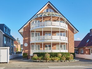 A multi-story building with a central atrium, balconies on each floor, and a brick facade.